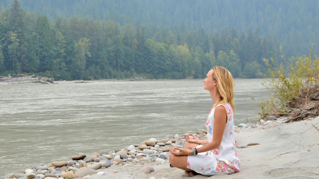 Woman meditating by a river during psychedelic integration process